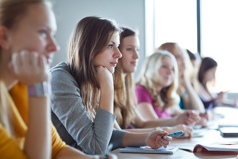 A group of young adults sat in a line at a desk