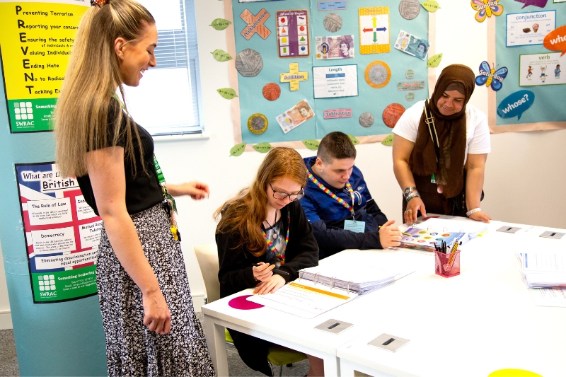 A group of young adults sat in a line at a desk