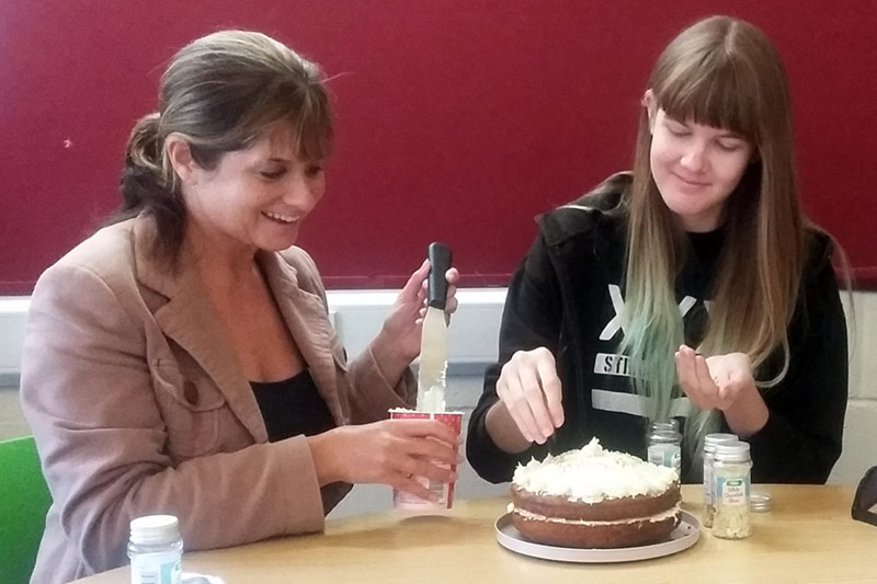 2 women decorating a cake