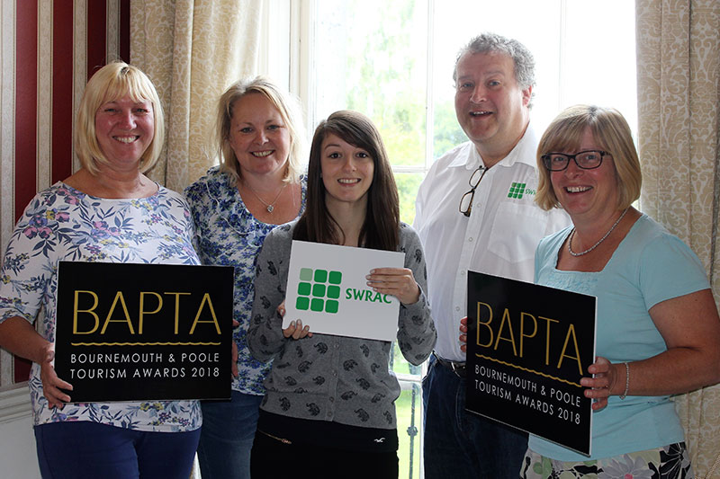 A group of 5 adults holding signs that say SWRAC & BAPTA, Bournemouth & Poole Tourism Awards 2018