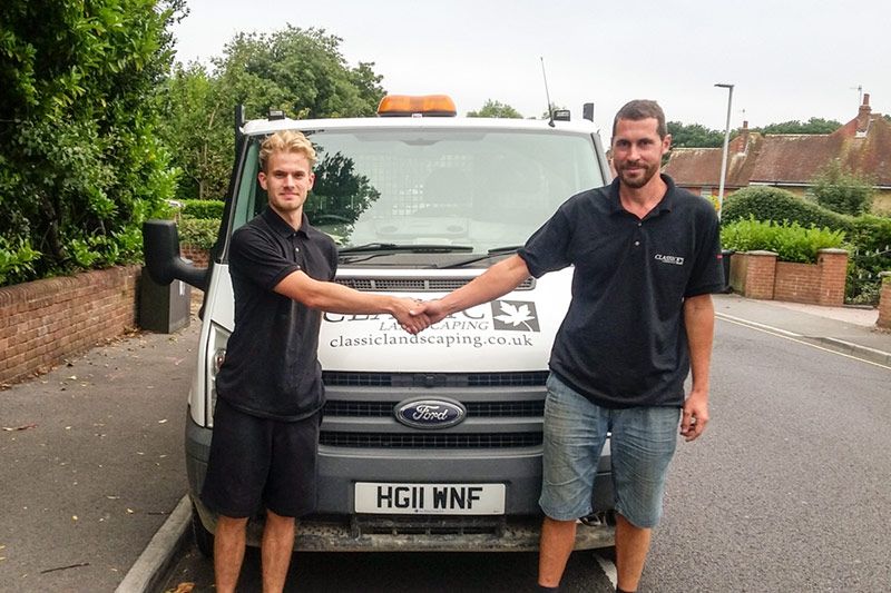 Two men stood in front of a work van shaking hands